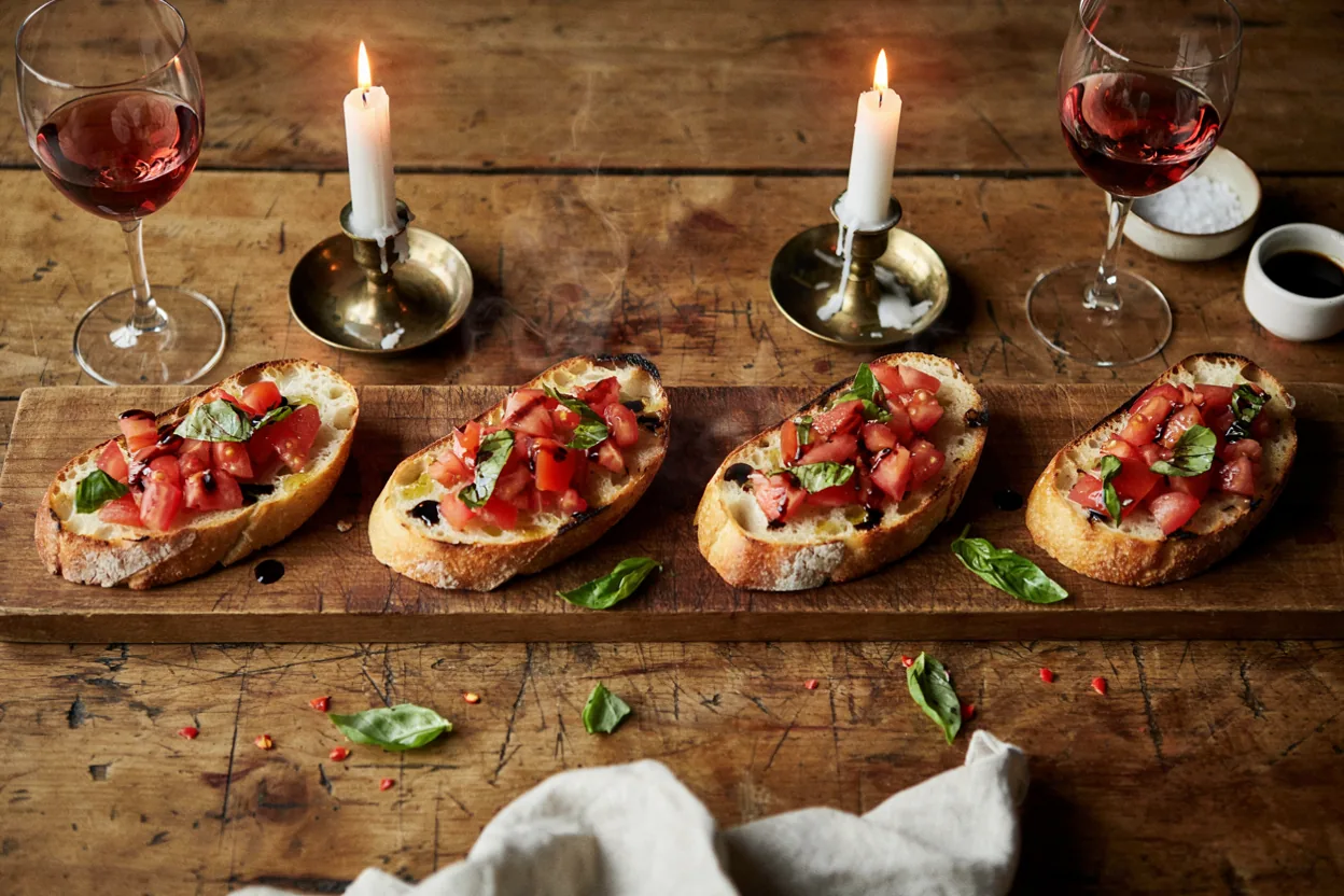 Bruschetta sa svežim paradajzom i zelenim bosiljkom na rustičnoj drvenoj dasci